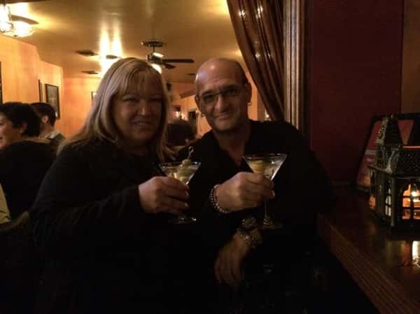 a couple smiling at the bar holding martinis