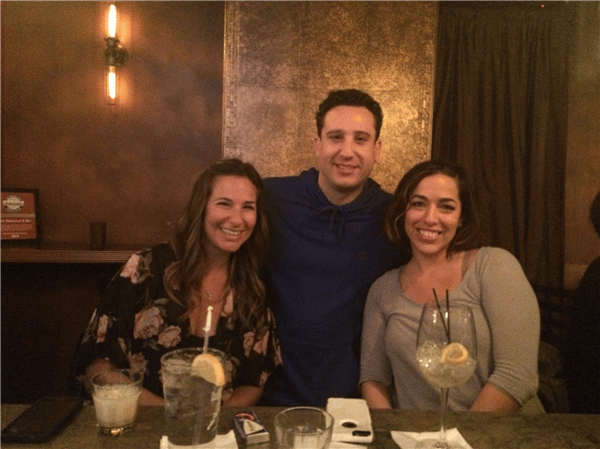 3 customers smiling with drinks aroun the bar
