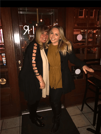 two customers smiling and posing by the door