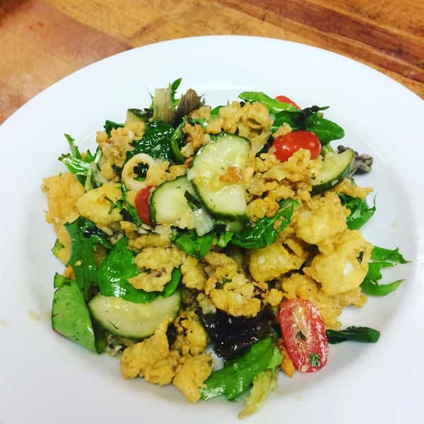 Salad topped with cucumbers, tomatoes, and calamari