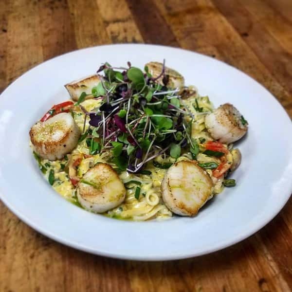 Pan-Seared Scallops, Thai Curry Coconut Sauce, Peppers, Onions, Scallions Served over Rice Noodles.