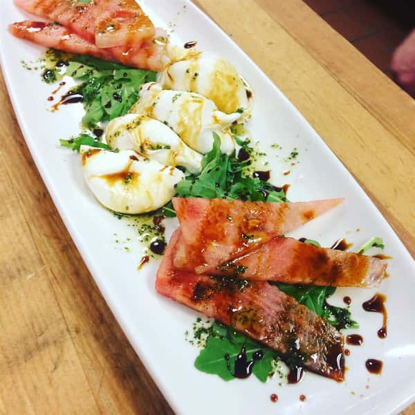 Slices of tomato and fresh mozzarella cheese topped with balsamic vinaigrette