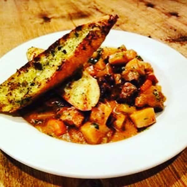 Sauteed vegetables on a plate topped with garlic bread
