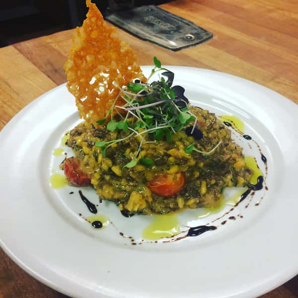 Bean and Corn mixed with brown rice topped with garnish and a fried chip
