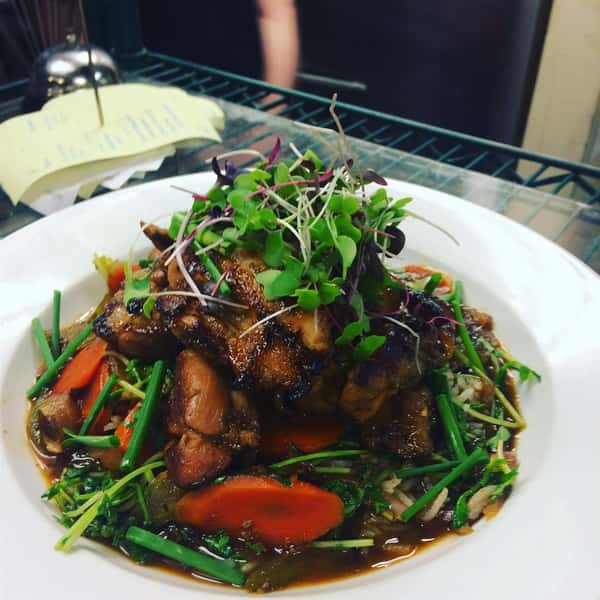 Roasted chicken topped with mushrooms and carrots and garnish in a sauce
