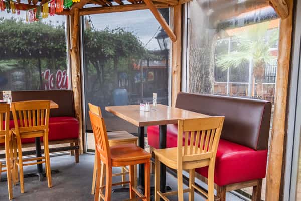 Bright and inviting restaurant dining area with wooden tables, comfortable booth seating, large windows, and a cozy atmosphere for casual Mexican dining.