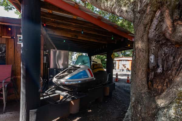 Retro jet ski stored under a wooden overhang beside a rustic lakeside building, adding quirky outdoor charm to the Cherry Pocket property.