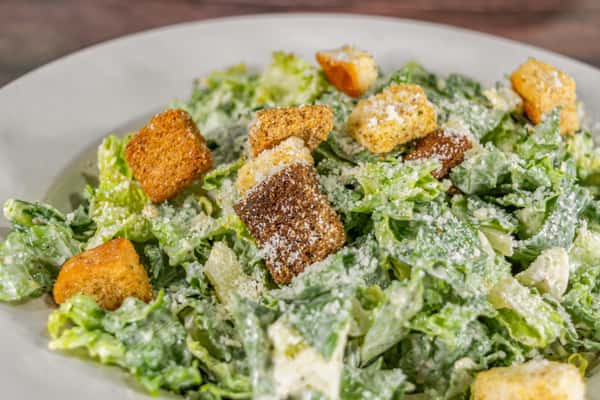 Fresh Caesar salad with crisp romaine lettuce, crunchy croutons, and a generous dusting of grated parmesan cheese, tossed in a creamy Caesar dressing.