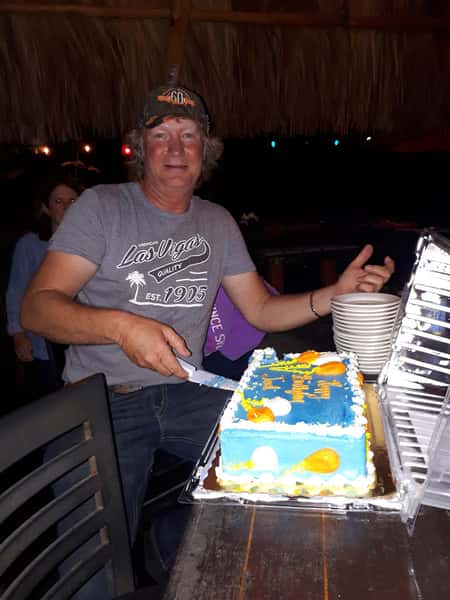 man posing for photo cutting cake