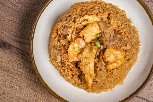 Fried rice mixed with shrimp, beef, chicken, egg, and vegetables, garnished with chopped green onions.