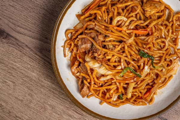 Stir-fried lo mein noodles with beef, cabbage, carrots, and scallions in a savory brown sauce on a white ceramic plate.