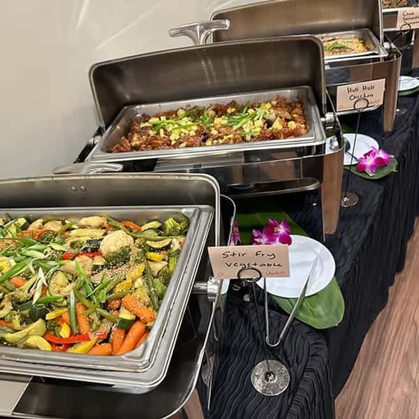 Chafing dishes lined up on a table filled with Hawaiian food
