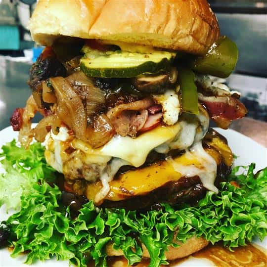 large cheeseburger with onions, tomatoes, pickles and ham