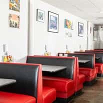 Row of retro-style red and black diner booths against a white wall with colorful framed artwork.