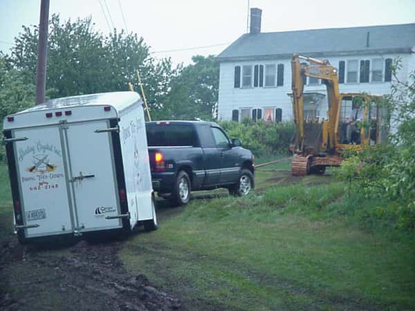 excavator truck pulling another truck out of the mud