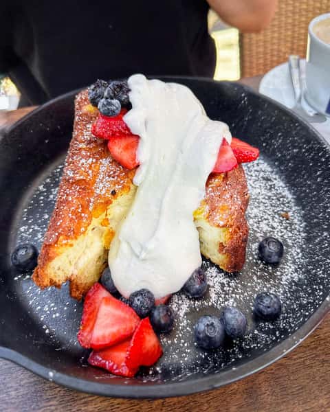 Breakfast entree with whipped cream, berries, and powdered sugar