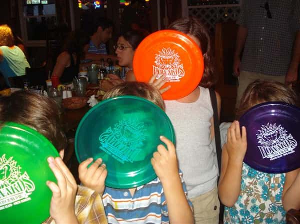 Children holding up Howard's Pub frisbees inside restaurant