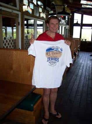 Woman holding up Howard's Pub t-shirt on patio.