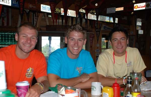 Three men at bar smiling for photo