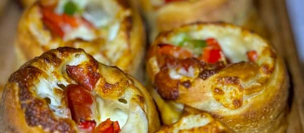 Pizza rolls filled with melted cheese, pepperoni, and vegetables, baked to a golden brown.