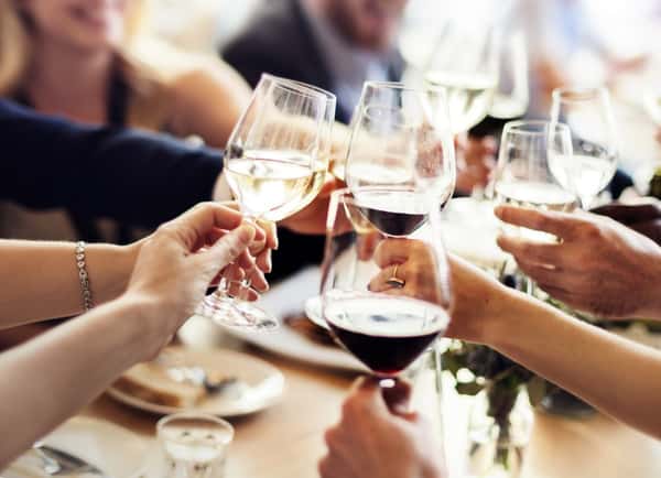 Group of people toasting with glasses of red and white wine at a celebratory gathering.