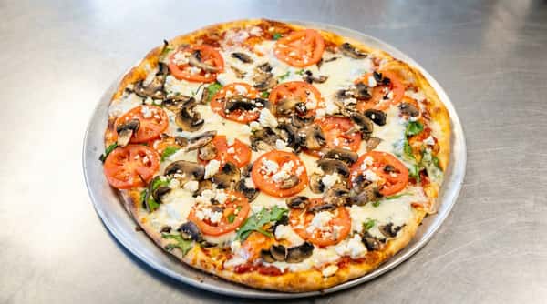 Pizza with shredded chicken, sliced tomatoes, basil, mozzarella, and a balsamic drizzle in a cardboard box.