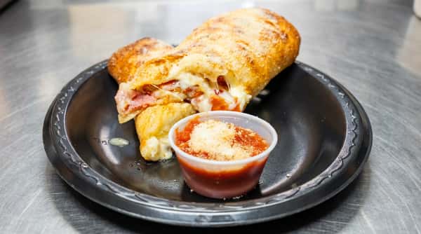 Calzone, sliced open to show melted cheese and meat filling, with a side of marinara sauce.