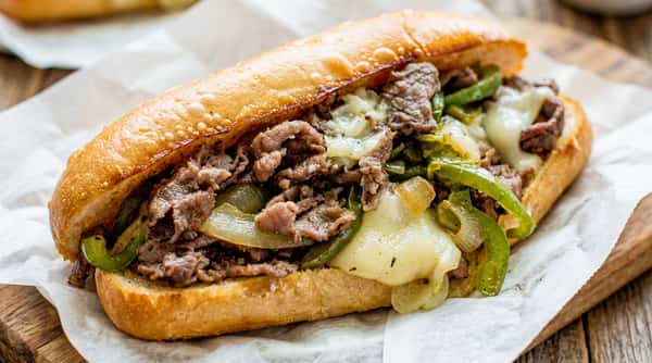 Cheesesteak sandwich with steak, melted cheese, and green peppers in a toasted bun.