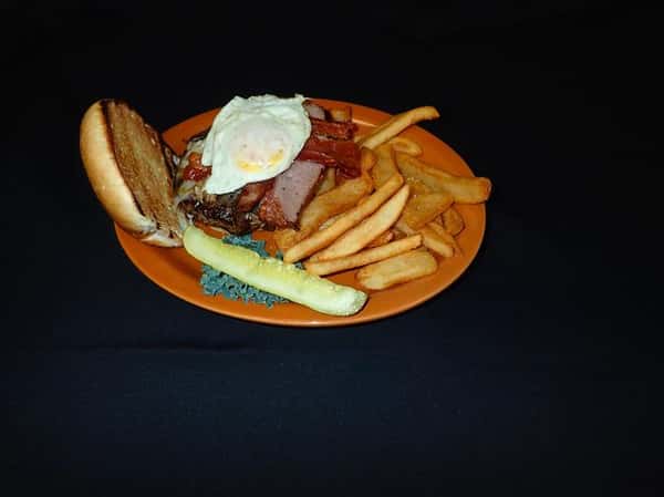 a burger with an egg over easy with a side of fries and a pickle on an orange plate