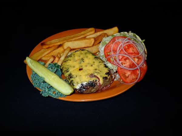 a burger without a bun with cheese, tomato, lettuce, and red onions with a side of fries and a pickle on an orange plate