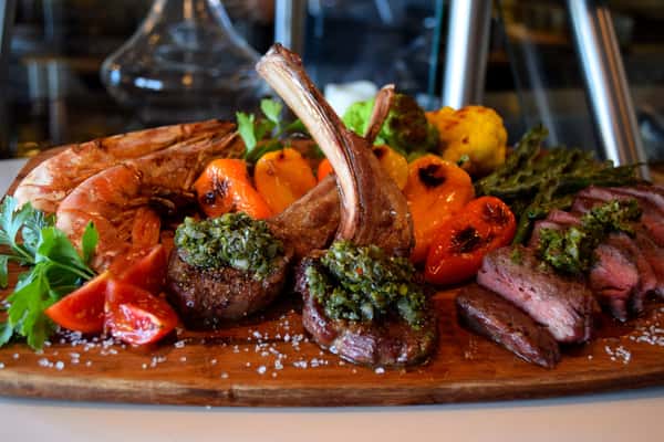 A mouthwatering platter featuring flame-grilled lamb chops, jumbo shrimp, and roasted peppers, bursting with vibrant flavors and colors at Maro Wood Grill.