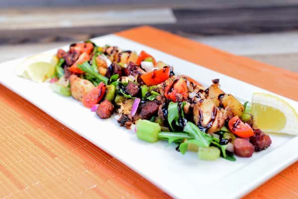 Tender grilled octopus tossed with roasted potatoes, cherry tomatoes, celery, chorizo, and fresh greens, finished with a balsamic glaze and lemon wedges — a vibrant Mediterranean-inspired dish packed with bold flavor and texture.