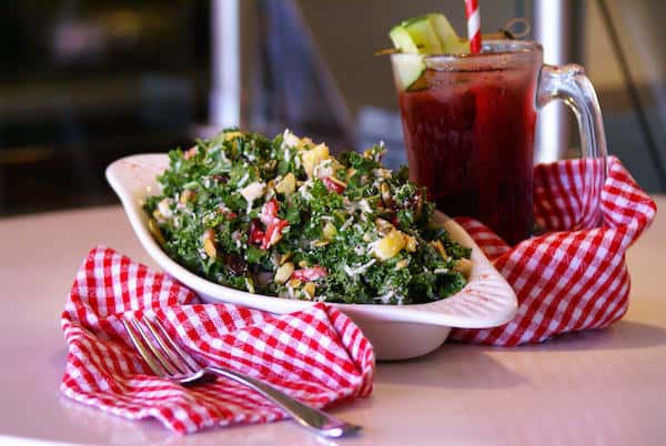 Fresh chopped kale tossed with seasonal fruit, toasted seeds, parmesan, and a light vinaigrette — a vibrant, nutrient-packed salad perfect for wholesome lunch or plant-forward dining.
