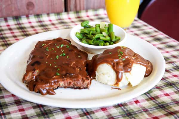 A savory country-style steak dinner served with mashed potatoes and gravy, fresh green beans, and rich homemade sauce. This hearty entrée delivers warm comfort and classic diner flavor in every bite.