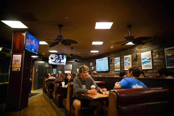 casual pizza restaurant interior with booth seating, wall art, and TVs showing sports
