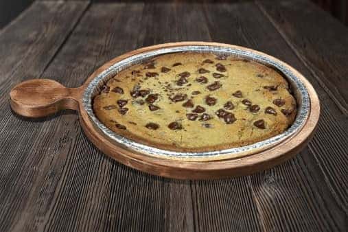 chocolate chip cookie dessert pizza baked golden and served on a wooden tray