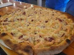 Reuben-style pizza topped with sauerkraut, corned beef, melted cheese, and a drizzle of dressing on a thick, golden crust.