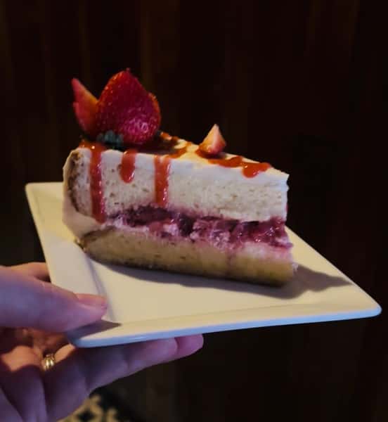 Sponge cake soaked in three milks, topped with cinnamon, whipped cream, and macerated strawberries