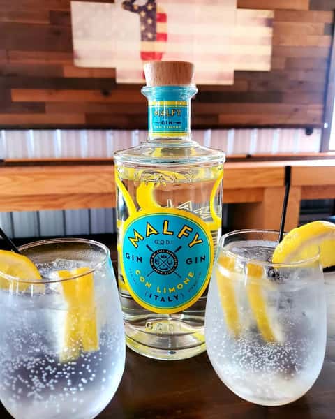 bottle of vodka with two glasses a lemon wedges