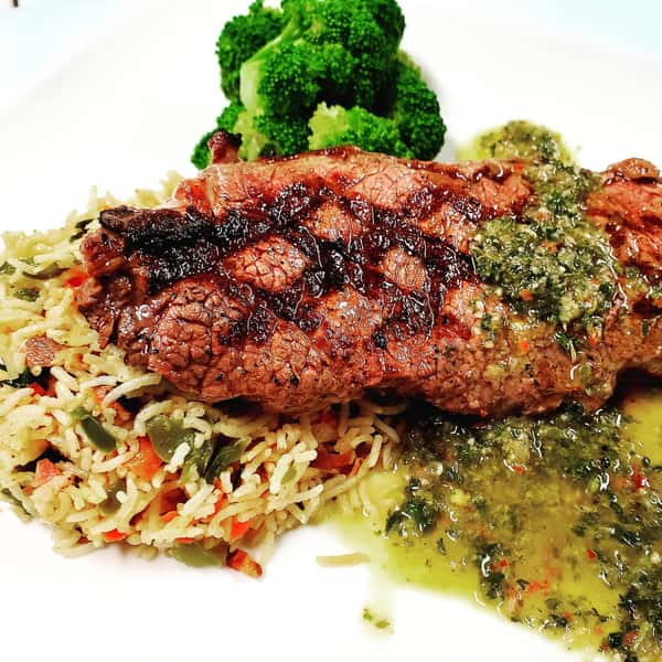 grilled steak over a side of rice with broccoli on the side