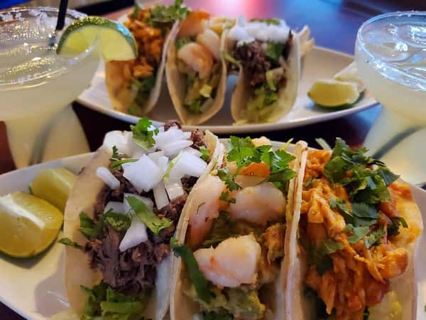 three tacos on a dish with a lime wedge