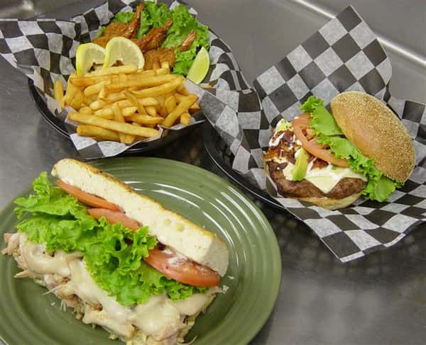 cheeseburger with lettuce, tomato in a basket. french fries and a salad in a basket. half of sandwich with lettuce and tomato on a plate.