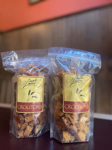 Two clear bags of homemade granola are neatly packaged and displayed, each sealed with a label. The granola appears packed with oats and natural ingredients, highlighting a fresh, artisanal product perfect for breakfast or a wholesome snack.