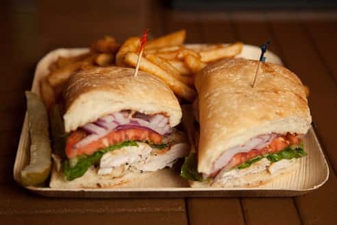 club sandwich cut in half with a pickle and french fries