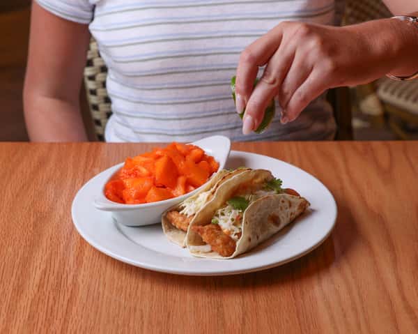 Crispy wrap served with fresh fruit and sweet potato fries.
