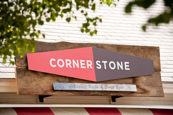 Corner Stone restaurant exterior sign for artisanal pizza and craft beer mounted on rustic wood facade