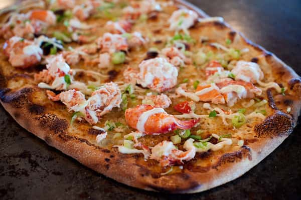 Wood-fired lobster pizza with melted cheese, herbs, and crispy artisan crust