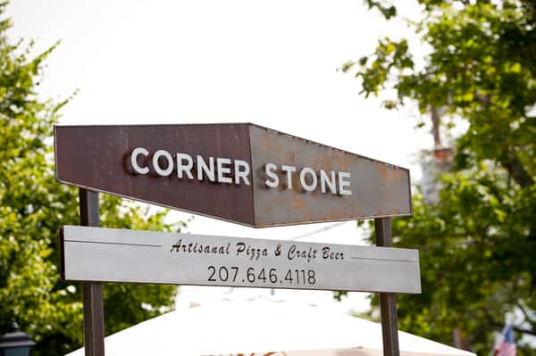 Corner Stone sign for artisanal pizza and craft beer with phone number on outdoor post