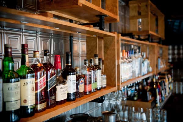 Bar shelves stocked with whiskey, bourbon, and liquor bottles in a rustic restaurant