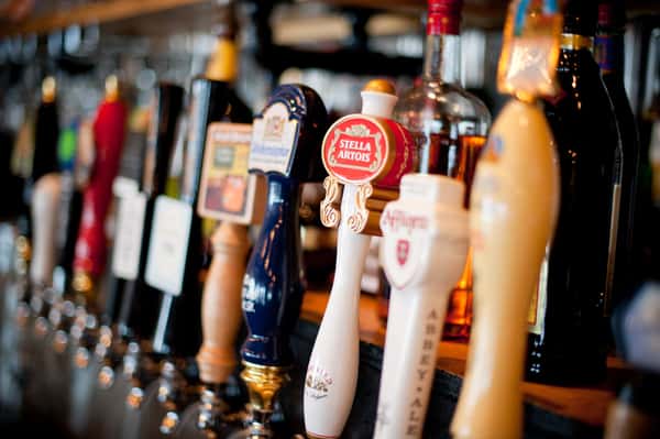 Bar lineup with assorted craft beer taps including Stella Artois, set against a warm, softly lit restaurant backdrop
